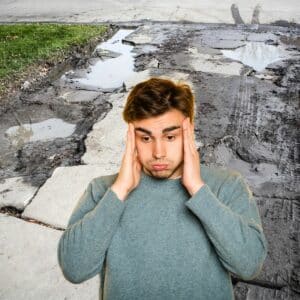 Man frustrated and overwhelmed in front of a cracked concrete driveway. Meant to depict an overwhelmed customer
